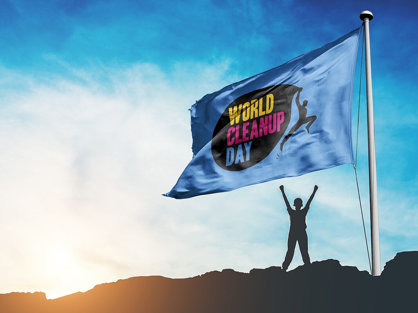 Eine Person steht mit hochgestreckten Armen neben einer Flagge mit der Aufschrift World Cleanup Day