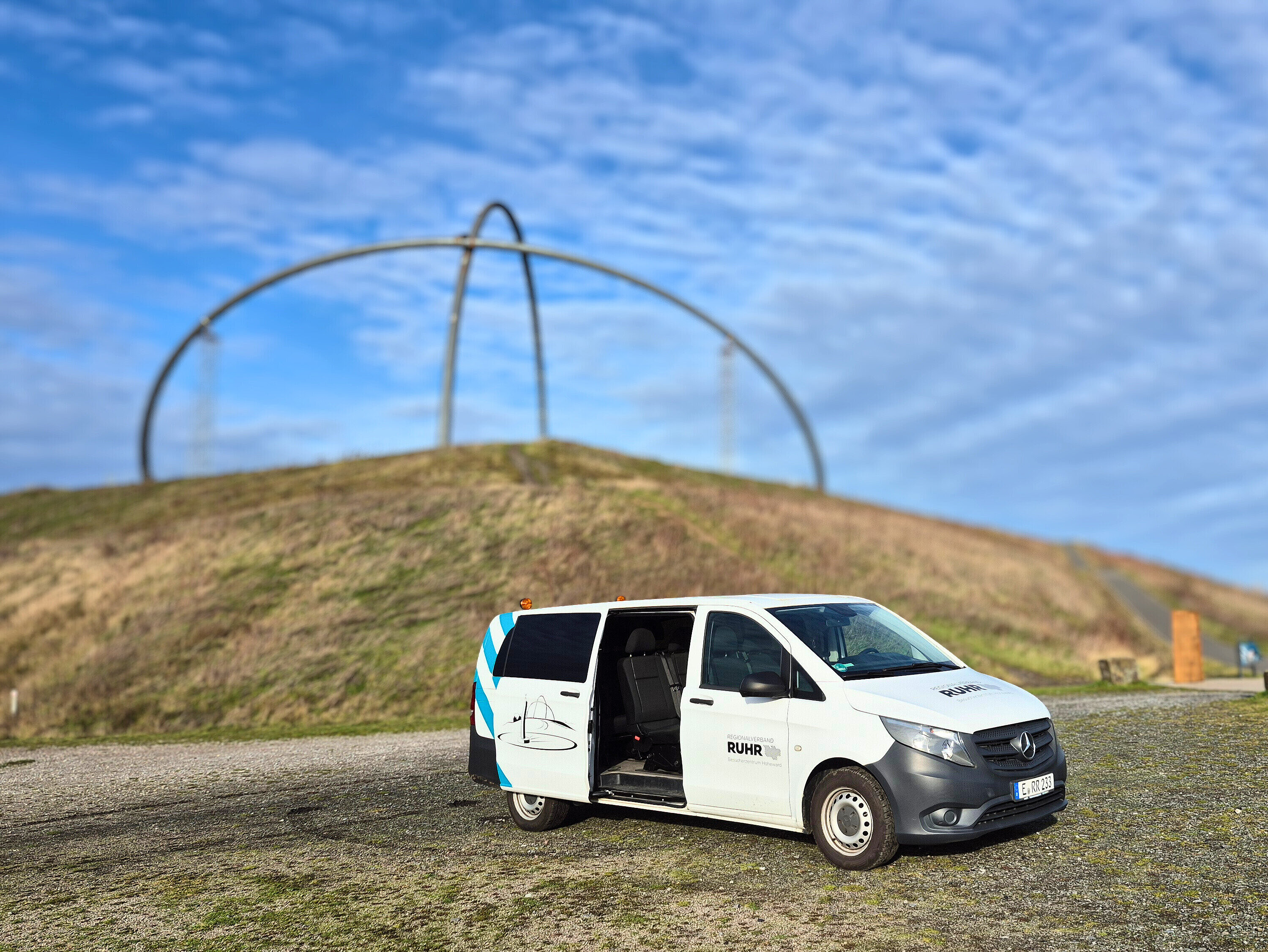 Ein großes Auto mit offener Tür steht auf einer Ebene der Halde Hoheward. Im Hintergrund ist das Horizontobservatorium zu sehen.  